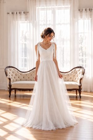Emma Lace Dress featuring a delicate lace bodice, adjustable shoulder tie straps and a flowing soft mesh skirt in a romantic bridal-inspired design.